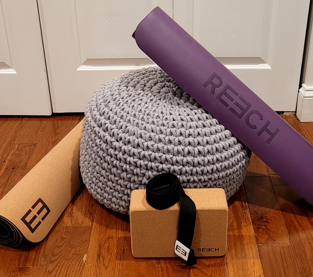 A non-slip purple yoga mat, cork yoga mat, yoga block, and carrying strap.