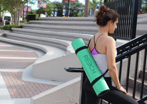 Woman traveling with a REECH non slip yoga mat in a convenient carrying strap outside.